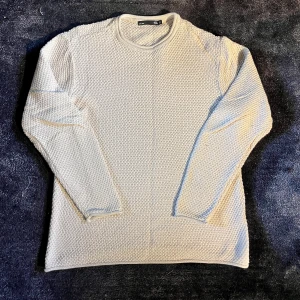 Beige stickad tröja från Selected Homme - Icke använd alls. Säljer en beige stickad tröja från Selected Homme i storlek L. Tröjan har ett grovt stickat mönster, rund hals och långa ärmar. Perfekt för dig som gillar enkel och clean stil med lite struktur. Passar dig som vill ha en normal passform och mjukt material.