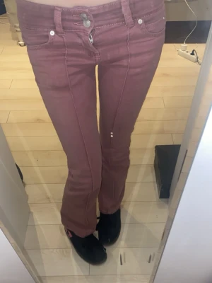 Rosa low waisted bootcut  - Säljer ett par rosa low waisted jeans med bootcut-modell, och markerade pressveck framtill. Jeansen har klassisk femficksdesign, dubbla knappar i midjan och dragkedja. Materialet är stretchigt denim för skön passform. Innerbenslängden är ca 79cm 🤍