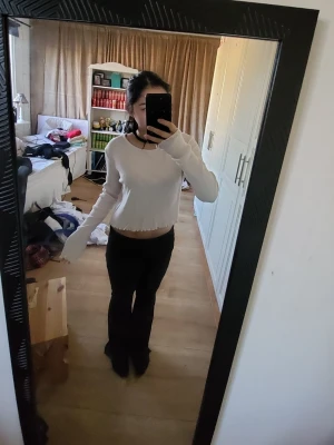 Vit croppad långärmad topp - Säljer en vit croppad långärmad topp med råa kanter och enkel design. Toppen har en rund halsringning och är tillverkad i ett mjukt bomullsliknande material. Perfekt för att styla med höga jeans eller kjol.