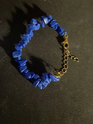 Blått armband med oregelbundna stenar - Snyggt armband med blå oregelbundna stenar trädda på en tråd och guldfärgat justerbart spänne. Perfekt för dig som gillar färg och unika detaljer. Stenarna har en cool, naturlig form som ger armbandet en trendig vibe.OBS! Materialet är okänt, kan ej garantera att det är rostfritt.