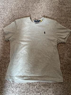 Ralph Lauren t-shirt - En grå Ralph lauren T-shirt som jag har använt 3 gånger. Den är lite mindre i storleken men inte mycket. Skriv för mer information!!