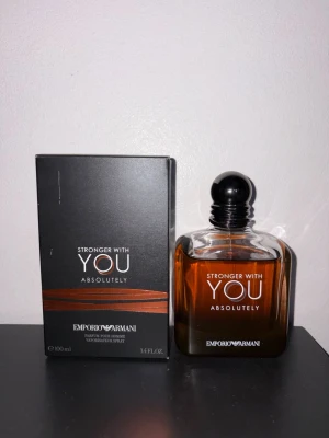 Emporio Armani Stronger With You - Emporio Armani Stronger With You Absolutely är en parfym med elegant design. Flaskan är fyrkantig med rundade kanter och har en mörk bärnstensfärgad vätska. Svart rund kork och stilren svart förpackning med vita och orange detaljer. Doften är maskulin och modern.