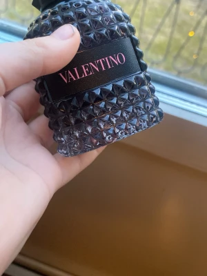 Valentino Born In Roma parfym - Säljer en Valentino Born In Roma parfym med en cool svart flaska täckt av nitar och rosa text. Flaskan har en lyxig och edgy design som verkligen sticker ut på hyllan. Kommer med originalkartong i matchande svart och rosa.