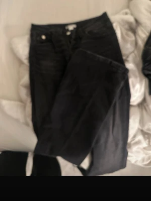 Svarta skinny jeans med fickor - Säljer ett par svarta skinny jeans med klassiska fem fickor och silverfärgade knappar. Jeansen har en smal passform och är tillverkade i stretchigt denimtyg för en bekväm känsla. Perfekta till en avslappnad streetstyle-look.