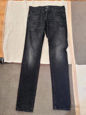 Svarta slim fit jeans med slitningar - Snygga svarta slim fit jeans med diskreta slitningar och tvättade detaljer. Klassisk femficksmodell med dragkedja och knapp i midjan. Jeansen har en smal passform och raka ben, perfekta till en avslappnad streetstil.