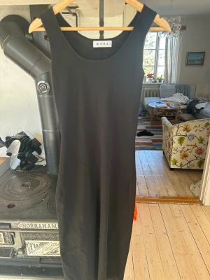 Svart långklänning från Wera - En stilren svart långklänning från Wera med ärmlös design och rund halsringning. Klänningen har en rak passform och är tillverkad i ett mjukt, stretchigt material som ger en bekväm känsla. Perfekt för dig som gillar minimalistisk och tidlös stil. 500-700 kr nypris.