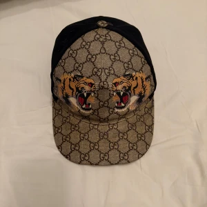 Mönstrad keps med tiger från Gucci - Perfekt keps inför sommaren, köpt här på Plick. Har knappt dock använt den bara under sommaren. Skicket på den är lätt en 9/10.