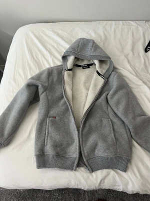 Grå fleecefodrad hoodie Schott NYC - Mysig grå hoodie från Schott NYC med dragkedja och huva. Insidan är fodrad med vit fleece för extra värme. Perfekt för kyliga sommar kvällar. ALDRIG ANVÄND! Storlek L men passar M också. Nypris 1500// mitt pris 500