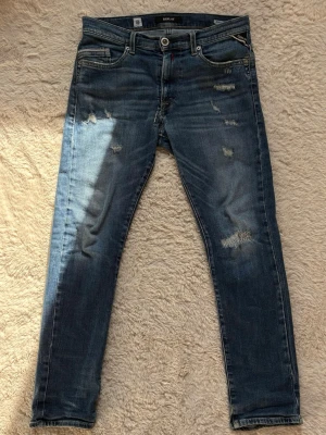 Blå slitna jeans från replay - Säljer ett par blå replay jeans med slitningar och raka ben. Perfekta för en casual stil. Jeansen är i storlek 158/164cm och är i väldigt bra skick✅ Fraktar inom en dag✅ Priset är inte hugget i sten🙂