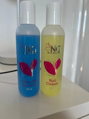 NG Nail Cleaner & Clean Off Solution (oöppnade) - Två flaskor från NG: en Nail Cleaner (gul, 90 ml) och en Clean Off Solution (blå, 90 ml). Perfekta för rengöring av naglar och borttagning av gelé- eller akrylrester. Praktiska plastflaskor med tydlig etikett och skruvkork. De är helt oöppnade!