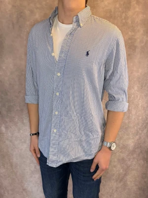 Randig Ralph Lauren Skjorta - Stl M, Classic fit - RIKTIGT FET RL SKJORTA I RANDIGT MÖNSTER MER FÄRGERNA SVART, BLÅ OCH VIT, perfekt till sommaren som närmar sig! 🏖️🌊 |Mycket bra skick: 9/10, utan defekter! | Stl: M |  Modellen är 176cm och väger 75kg,  | Hör av dig vid frågor // Galgen 🫡