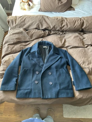 Marinblå kappa från Desigbysi - Marinblå kappa från Designbysi i storlek M/L. Fodrad insida och passar perfekt till våren och hösten. Lite nopprig men annars inga skavanker. Original pris 800 kr, pris kan diskuteras.