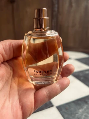 Forever parfym Laura Biagiotti 30ml - Elegant parfymflaska från Laura Biagiotti med namnet Forever. Flaskan är genomskinlig med mjuka, rundade former och har en roséguldfärgad spraypump. Innehållet är ljust bärnstensfärgat och flaskan känns lyxig och modern. Bara testad. Ingen parfymflaskans kork. 