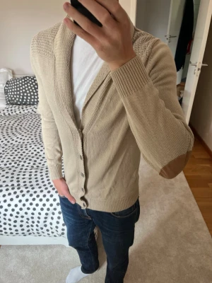 Beige kofta med armbågslappar - Snygg cardigan från Massimo Dutti i väldigt fint skick utan defekter! Tröjan är i storleken M! ✌🏼——————————————————————————                                                                      📐| Storlek: M                                                           👖| Märke: Massimo Dutti                                      🔎| Skick: Mycket Bra                                                     ✍🏻| Skriv om du har några frågor