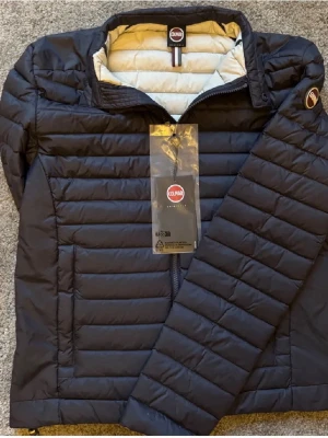 Mörkblå pufferjacka från Colmar - Snygg mörkblå jacka från Colmar med quiltad design och hög krage. Jackan har dragkedja framtill, Colmar-logga på ärmen och ljus insida. Perfekt för nu inför hösten och passar med allt. Köpt ny från Colmar, lite under ett år sen. Säljer pga att jag växt ut ur den. Självklart helt äkta. Pris går att diskutera så kom med förslag!