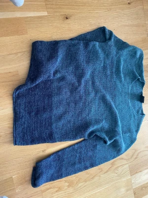 Blåmelerad stickad tröja från Smog - Snygg blåmelerad stickad tröja från Smog i storlek M. Tröjan har rund halsringning och långa ärmar. Perfekt för dig som gillar en enkel och stilren look. Materialet känns mjukt och bekvämt mot huden.