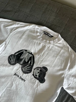 Palm Angels T-Shirt - Palm Angels x END t-shirt i mycket bra skick.   Storlek: M (oversized) ✨ Skick: Mycket bra ✨ Färg: Vit med grå nalle ✨  Var inte rädd för att ställa några frågor om tröjan, mått eller annat. Priset är lågt för en anledning😁