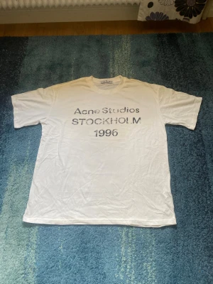 Acne studios vit tröja  - Acne Studios Stockholm 1996 T-shirt – Nyskick  Säljer en stilren och exklusiv T-shirt från Acne Studios med det ikoniska “Stockholm 1996”-trycket framtill. Tröjan är helt ny och endast provad, vilket innebär att den är i nyskick utan några anmärkningar.  ✨ Endast provad – aldrig använd ✨ Klassisk och tidlös design ✨ Mjuk och bekväm passform ✨ Perfekt till både vardag och streetwear  Skick: 10/10 – helt ny, endast testad Färg: Vit Märke: Acne Studios