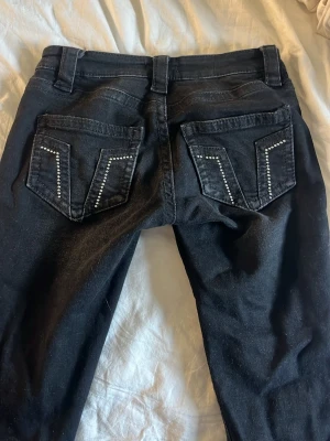 Svarta jeans med glitter paljetter från Gina Tricot - Snygga svarta jeans från Gina Tricot i storlek XS. Jeansen har vida ben och bakfickor dekorerade med silvriga paljetter i ett coolt mönster. Dom har blivit försmå! Och pågrund av att jag har korta ben så har de gått sönder på baksidan längst ner! Därav priset.