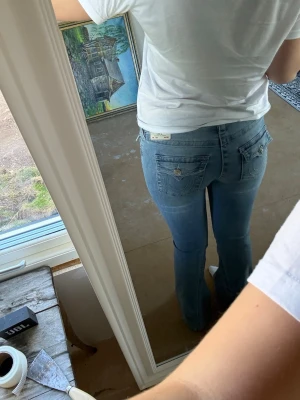 Ljusblå true religion bootcut jeans  - Säljer ett par ljusblå bootcut jeans från true religion med snygga fickdetaljer bak. Dom är lågmidjade och har klassisk femficksmodell. Perfekta för dig som gillar en avslappnad men ändå trendig look. Har knappt använt dom då dom är lite för stora på mig men älskar färgen🩷