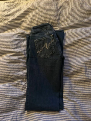 Blå bootcut jeans från Nelly - Säljer ett par klassiska blå bootcut jeans från Nelly med snygg kontrastsöm på bakfickan. Jeansen har normal midja och är tillverkade i mjukt denimtyg. Perfekta för dig som gillar en avslappnad men ändå trendig look.