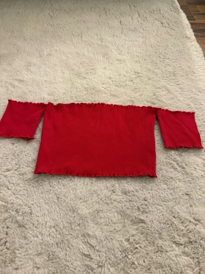 Offshoulder topp  - Trendig röd offshoulder topp från Missguided med ribbad struktur. Toppen har långa ärmar och en croppad passform som ger en snygg och modern look. 