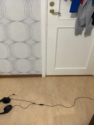 Svarta gaminghörlurar med mikrofon - Säljer ett par svarta over-ear gaminghörlurar med blå detaljer och inbyggd mikrofon på böjbar arm. Hörlurarna har kabelanslutning och vadderad bygel för extra komfort. Perfekta för gaming eller videosamtal.