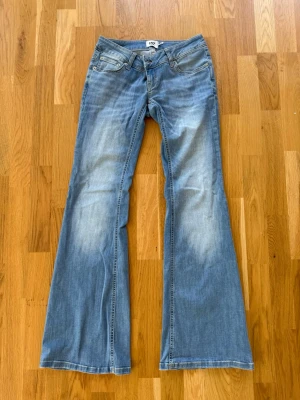 Blå lågmidjade jeans  - Säljer ett par ljusblå bootcut jeans från lager157. Midjemåttet: 36cm, Innerbenslängd: 83cm.