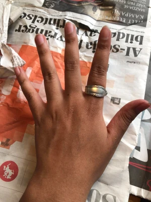 Bred silverfärgad ring med mönster - Säljer en bred ring i silverfärgad metall med dekorativt mönster längs kanterna. Ringen har en klassisk, tidlös design och passar perfekt för dig som gillar stilrena accessoarer. Enkel att matcha med andra smycken.