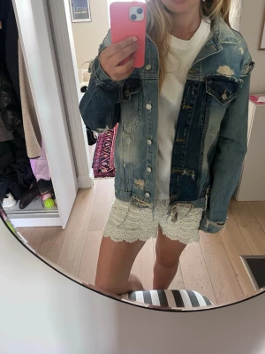 Patchwork jeansjacka i blå toner - Säljer en unik patchwork jeansjacka i olika blå nyanser med slitna detaljer och råa kanter. Jackan har bröstfickor med lock och knappar framtill. Perfekt för dig som vill sticka ut med en trendig och edgy look.