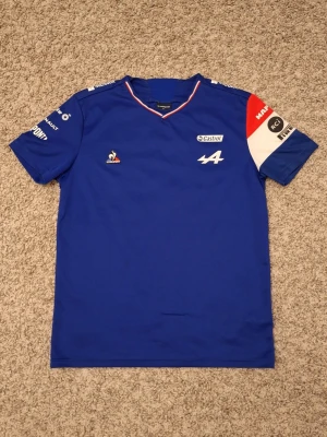 Alpine F1 Team Esteban Ocon 2021 Driver T-shirt Blå - Alpine F1 Team Esteban Ocon 2021 Driver T-shirt Blå, från Le Coq Sportif i storlek M. Använd fåtal gånger ich skicket är i princip som ny. Riktigt snygg, stilig och skön. Denna T-shirt är väldig sällsynt nu för tiden och finns endast i små kollektioner. Skick: 9/10