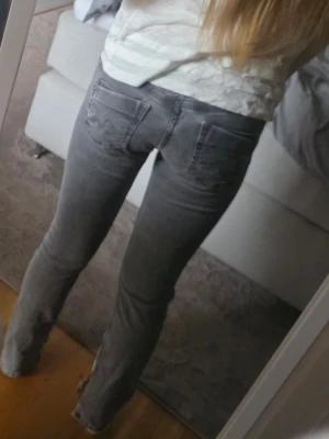 Grå raka jeans med slitningar - Säljer ett par grå jeans med rak passform och slitna detaljer vid fickorna. Jeansen har klassisk femficksdesign och normal midja. Perfekta för en avslappnad och trendig look. Materialet är denim i bomull.