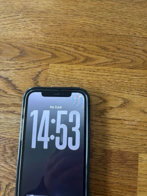 iPhone med svart skal och trippelkamera  - Säljer en iPhone med svart skal från MobileFriend. De är en 12 pro Telefonen har en stor skärm med tunn ram och en tydlig notch upptill. Baksidan har trippelkamera och blixt, samt Apple-loggan. Skalet är i plast och skyddar hela baksidan och kanterna.