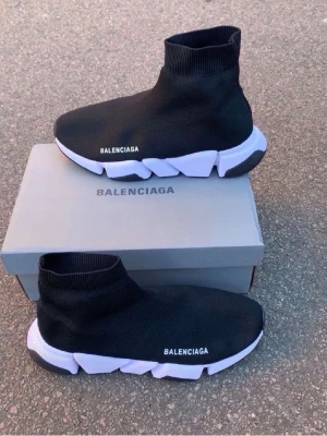  Speed Trainer svarta sneakers - Svarta  Speed Trainer sneakers med vit chunky sula och stickad strumpdesign. Skorna har logga på sidan och en elastisk ovandel i textil som sitter tight runt foten. Sulan är grov och futuristisk med svarta och vita detaljer.