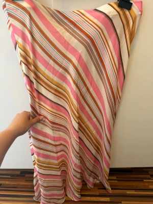 Randig långkjol från Zara - Säljer en färgglad långkjol från Zara med diagonala ränder i rosa, orange, vitt, brunt och gult. Kjolen har en flowy passform och är tillverkad i ett lätt material som passar perfekt för varmare dagar. Supersnygg till både sneakers och sandaler!