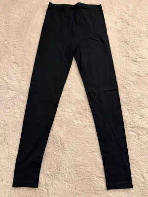 Svarta leggings - Säljer ett par klassiska svarta leggings från Monki. De har hög midja och är tillverkade i ett mjukt och stretchigt material som sitter skönt mot kroppen. Perfekta att matcha med oversized tröjor eller hoodies. Står ej storlek men gissar på Xs 