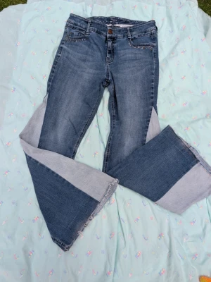 Blå utsvängda jeans med strass - Remake gjorda av mig! Säljer ett par blå jeans med utsvängda ben och råa kanter längst ner. Jeansen har dekorativa nitar vid fickorna och en klassisk femficksmodell. Materialet är denim i bomull och de har en cool vintagekänsla.