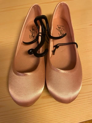 Ljusrosa satängballerinaskor - Snygga ljusrosa ballerinaskor i satängliknande material från City Street. Skorna har rund tå och en klassisk, enkel design med mjuk innersula och mönstrad yttersula för bättre grepp. Perfekta för dig som gillar stilrena och feminina skor. Står storlek 5!