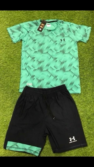 Under Armour träningsset grön/svart - Snyggt träningsset från Under Armour med en grön t-shirt i geometriskt mönster och svarta shorts med grön detalj. T-shirten har rund hals och kort ärm, shortsen har resårmidja och dragsko. Perfekt för gym eller löpning.