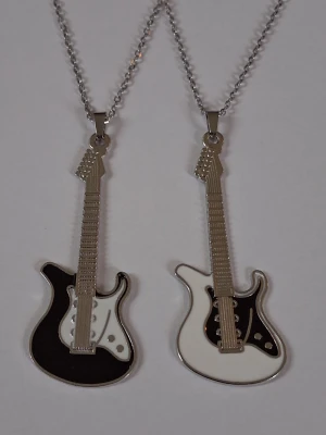 2 stycken Halsband med elgitarrer  - Två halsband med coola elgitarr-hängen i metall. Ena hänget är svart och vitt, det andra vitt och svart, båda med detaljer i silverfärg. Båda två ingår I priset. Materialet rostfritt stål. 