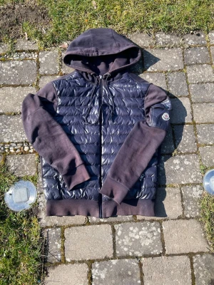 Moncler cardigan  - Hej, säljer denna Moncler cardigan, jag tror att den är äkta, eftersom allt som ska va äkta att kolla på är äkta, men har inget kvitto eller liknande, jackan är M och passar mig som är 188cm och 75kg, defekterna syns på bild(små hål och solblekt.