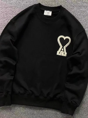 Svart sweatshirt från Ami Paris - Svart sweatshirt från Ami Paris med rund hals och ribbade muddar. På bröstet sitter ett stort vitt Ami-hjärta med bokstaven A. Perfekt för en clean och stilren look.