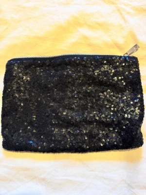 Ny Svart paljettkuvertväska - Ny Kuvertväska i paljett. Med dragkedja.  Fest! Ca 27x19cm. Ett fack inuti. Hämtas på Hägerstensåsen eller skickas. 