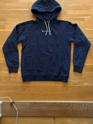 Hoodie - En mörkblå hoodie av champion med vita snören 
