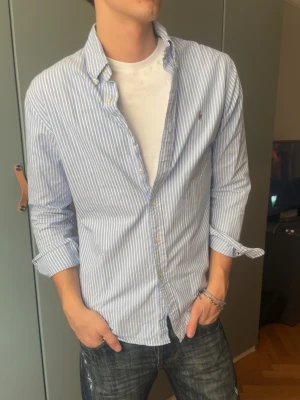 Blårandig skjorta från Ralph Lauren - Ralph Lauren skjorta, inga defekter! Modellen är 187 och väger 80 kg, klär i M. Axelmått är 50 cm, längd är 74 cm. Pris går att diskuteras vid köp av bundle. Det är bara att skriva ifall du har nån fråga ✨