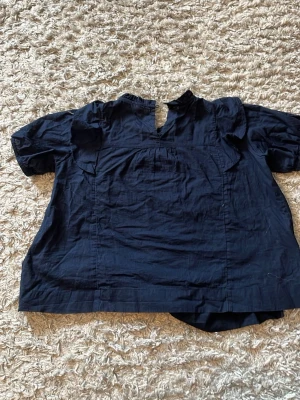 Marinblå blus från Gina tricot  - Marinblå blus från Gina tricot. Den knäpps med en knapp där bak. Den är i väldigt bra skick. Den har broderi där fram och volang på axlarna. I 146-152. 