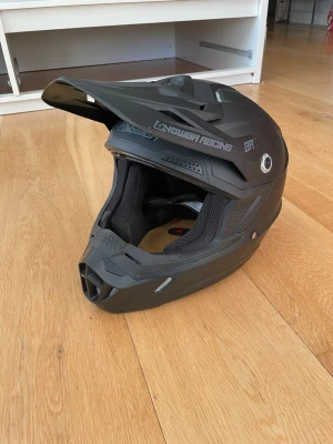 Svart crosshjälm Answer Racing AR1 - Säljer en svart crosshjälm från Answer Racing med matt finish och robust design. Hjälmen har ventilation, skärm framtill och vadderad insida för extra komfort. Perfekt för motocross eller offroad-äventyr.