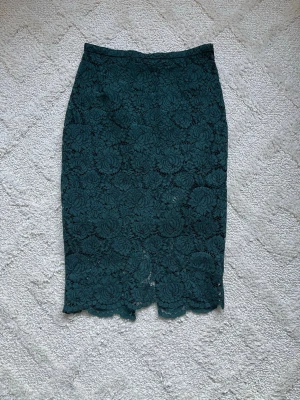 Grön spetskjol med blommönster - Snygg grön spetskjol med blommigt mönster och figurnära passform. Kjolen har en elegant spetsyta och är helfodrad med mjukt tyg på insidan. Perfekt för dig som vill ha en stilren men ändå unik look.