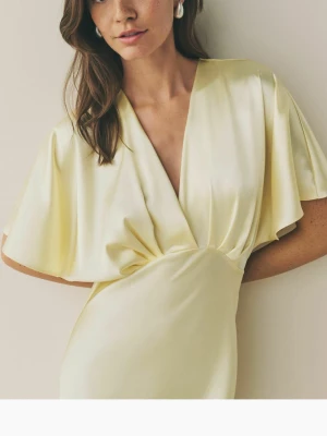 Ljusgul långklänning i satin - Elegant ljusgul balklänning i satin med v-ringning, lite omlott, och vida korta ärmar. Helt oanvänd med lappen kvar, säljer för att jag hittade en annan. Köpte på zalando för 1400. Buda gärna!