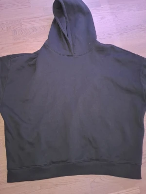 Mörkgrön oversized hoodie - En enkel och stilren mörkgrön hoodie i oversized modell. Hoodien har en stor huva och breda muddar nedtill. Tillverkad i mjukt bomullstyg som känns skönt mot huden. Perfekt för en avslappnad och chill look.